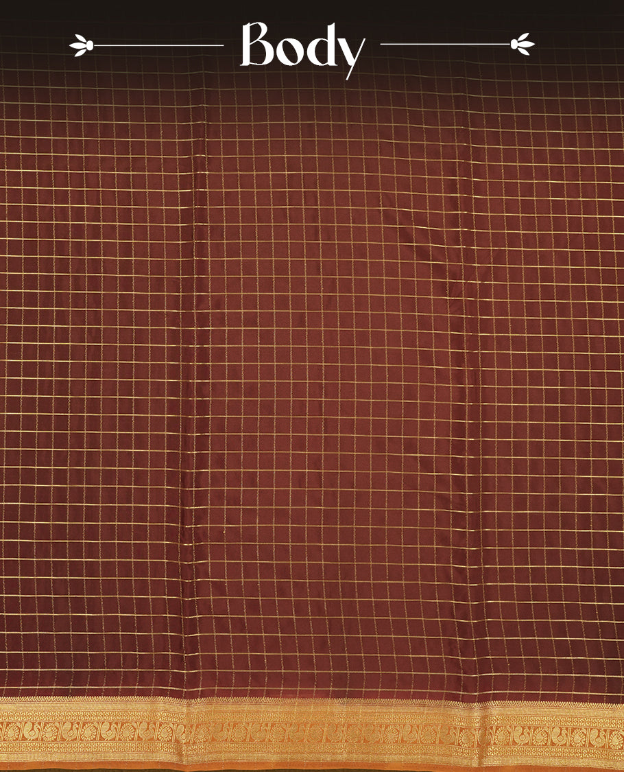 Dark Choclate colour mysore crepe saree with gold zari check pattern on body, complemented by contrast dark mustard colour border featuring peacock and chakkram motifs, paired with matching blouse.