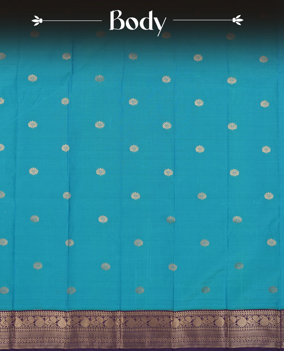 Teal Blue Colour Semi Silk Saree with Golden Peacock Butta Motifs, Contrasting Purple Golden Zari Pallu & Border, Traditional Leaf Designs, and Matching Blouse Piece