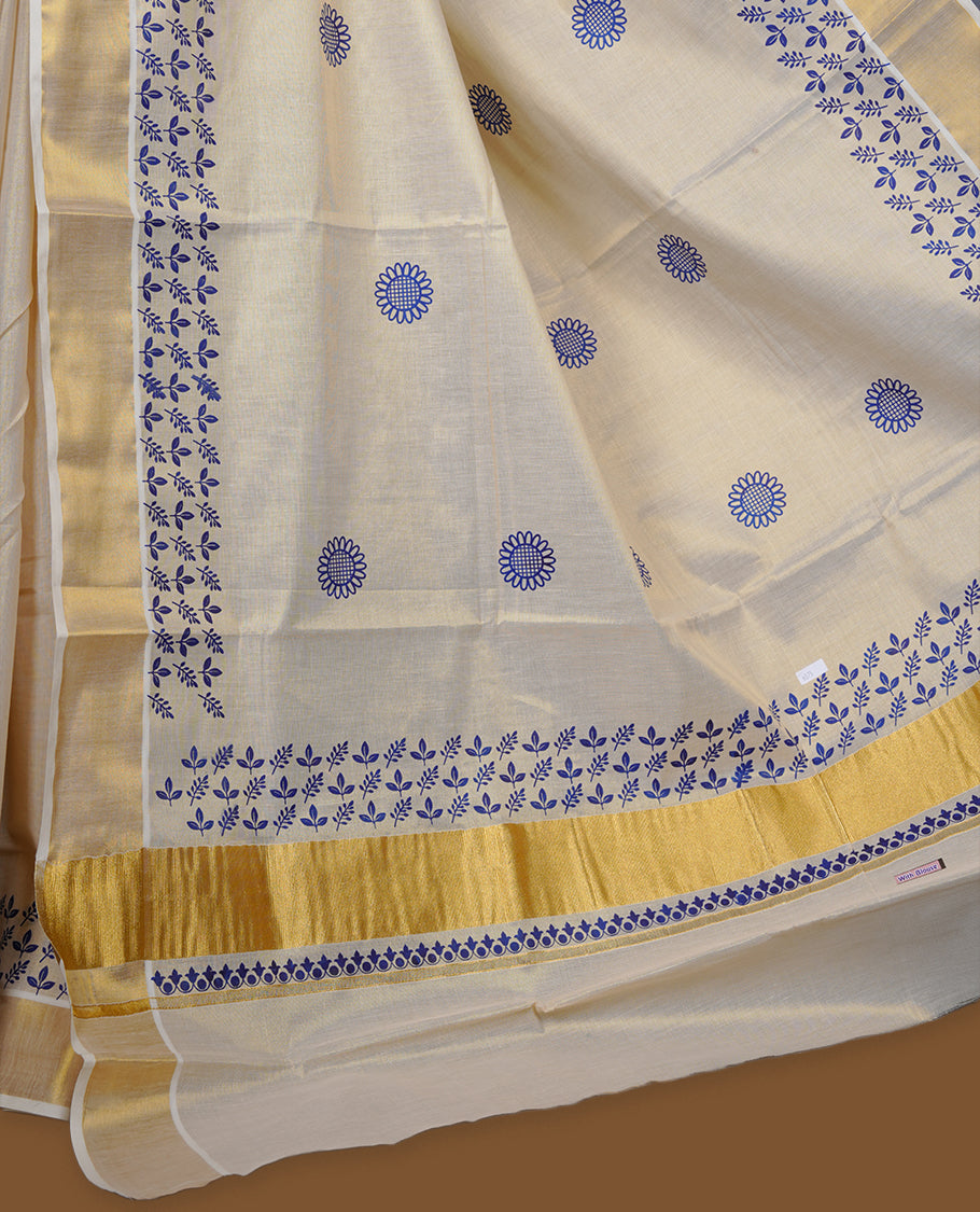 Off-white colour tissue Kerala saree with a rich gold kasavu border, adorned with delicate royal blue floral motifs across the body and pallu, paired with a matching blouse.