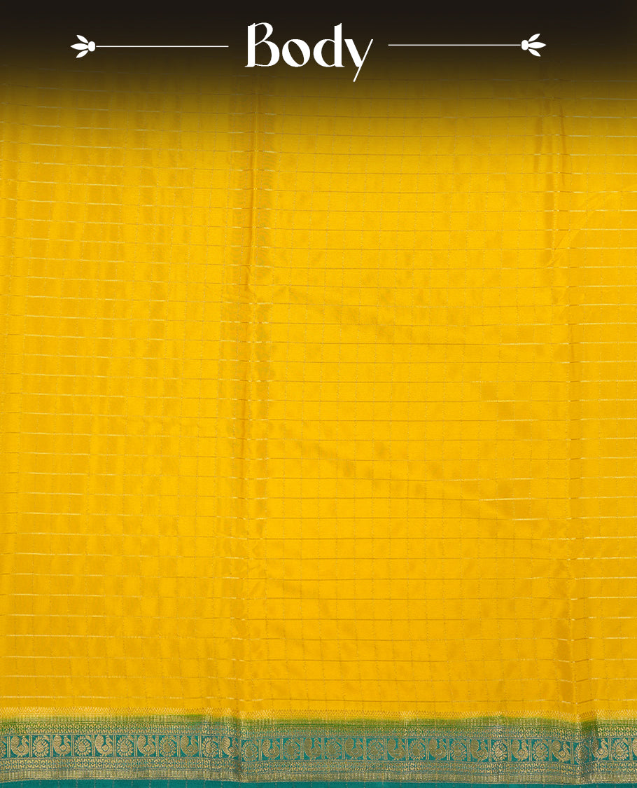 Yellow colour mysore crepe saree with gold zari check pattern on body, complemented by contrast Green colour border featuring peacock and chakkram motifs, paired with matching blouse.