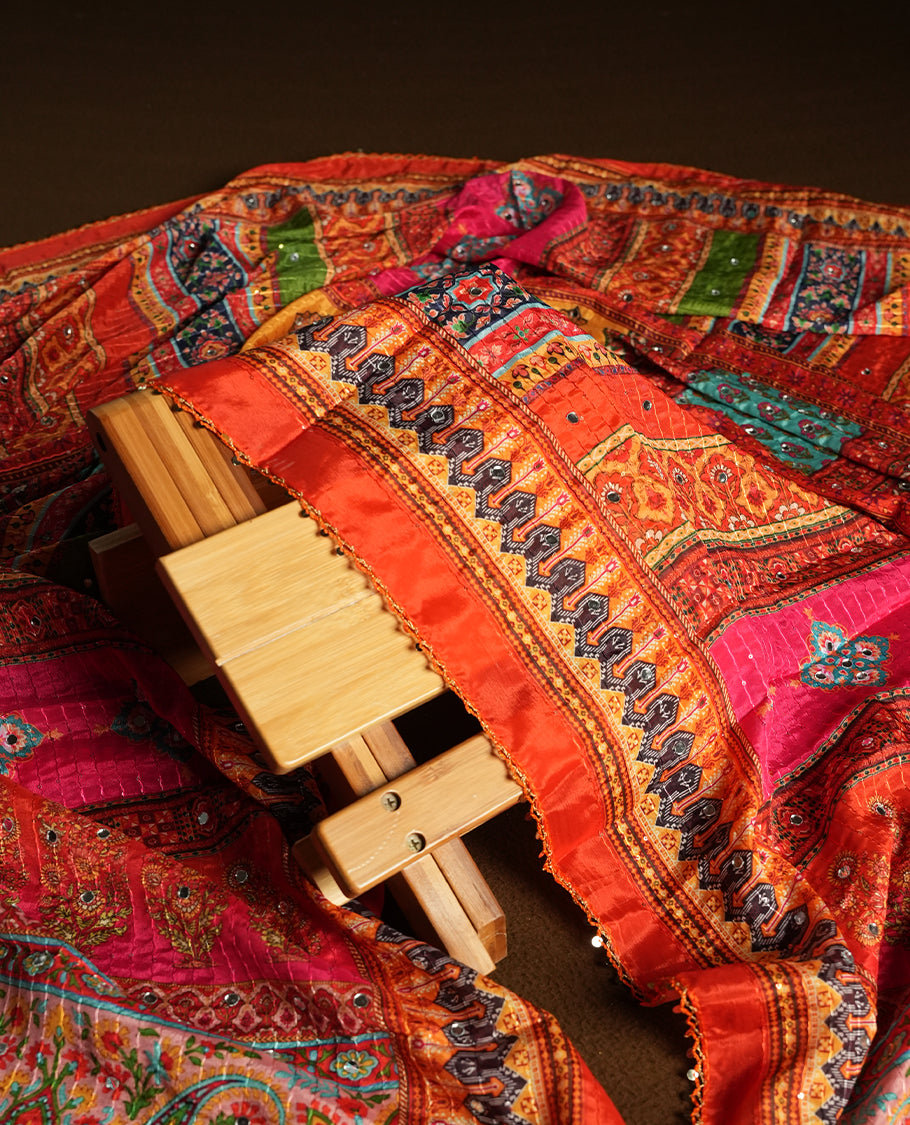 White colour churidhar material featuring Mirror and thread embroidery & foral print pattern on the contrast Dark orange colour front panel, floral digital printed dupatta with elegant border, and matching plain bottom