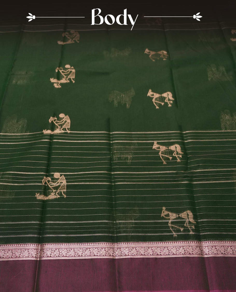 Green Colour silk cotton saree with scattered gold Warli animal motifs, gold horizontal stripes, ornate pink and gold zari border with floral patterns, gold zari pallu with diamond lattice and Warli dancer motifs, wine purple blouse.