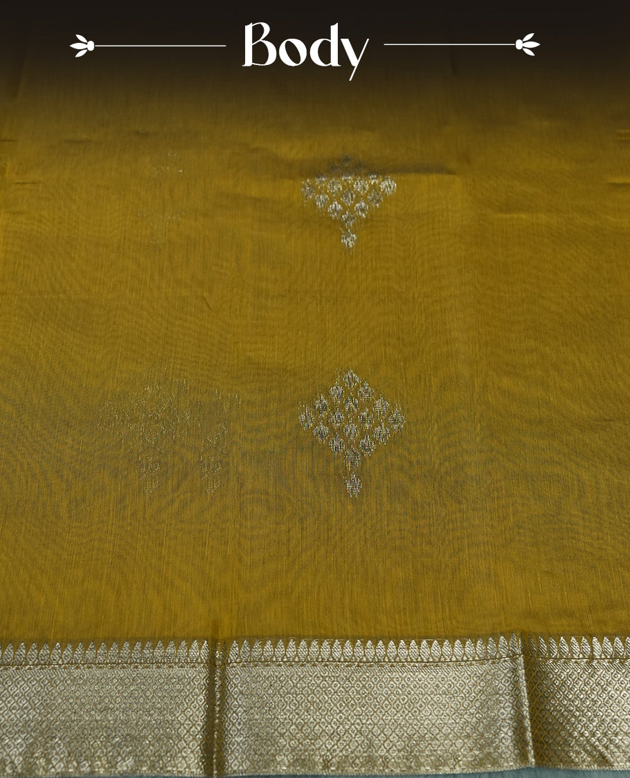 Bronze yellow colour silk cotton saree adorned with silver zari buttas and a rich zari border, complemented by a finely woven pallu & Paired with a matching blouse, perfect for festive gatherings and traditional occasions.