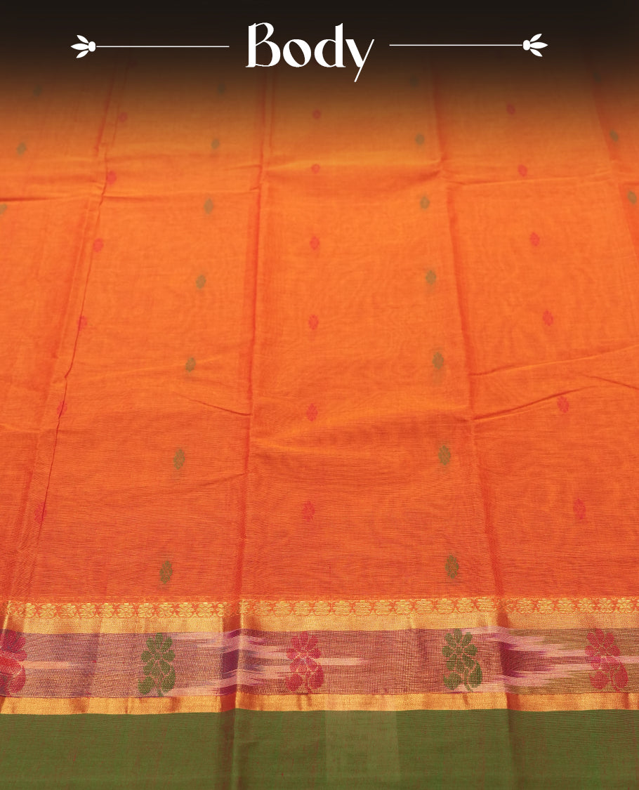 Burnt Orange colour Silk Cotton Saree with Contrast Green Zari Border featuring Ikat-inspired floral panels, Small Dual-Tone Buttas on the Body, Paisley-Woven Pallu, and a Coordinated Matching Blouse Piece