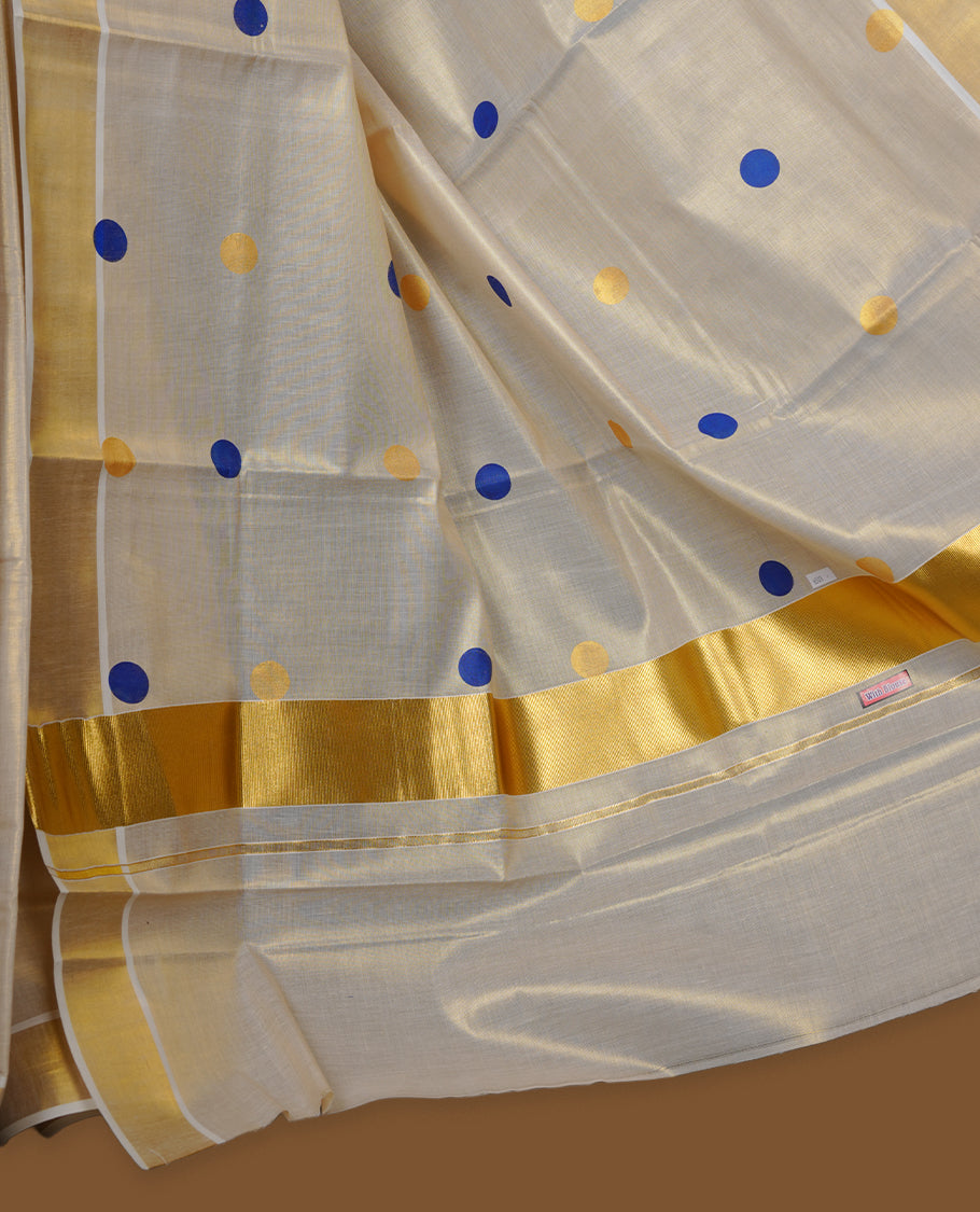 Off-white colour Tissue Kerala saree featuring playful blue and gold polka buttas across the body, finished with a classic gold kasavu border and paired with a matching blouse.