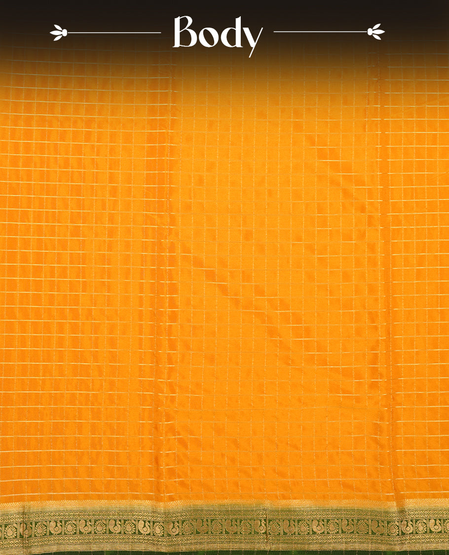 Mustard colour mysore crepe saree with gold zari check pattern on body, complemented by contrast Green colour border featuring peacock and chakkram motifs, paired with matching blouse.