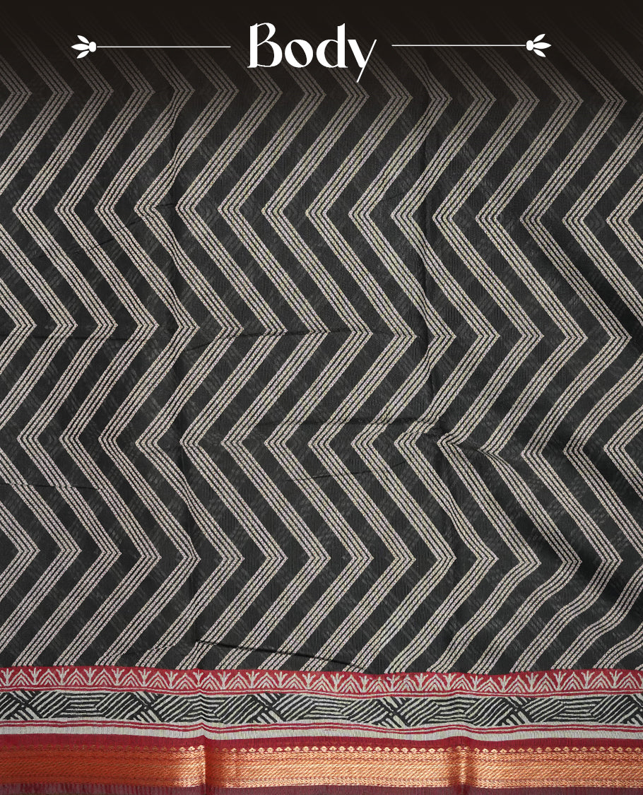 Black colour mixed chanderi cotton saree with ashy white zari body, red and black geometric pallu with floral motifs, gold border, and matching black blouse.