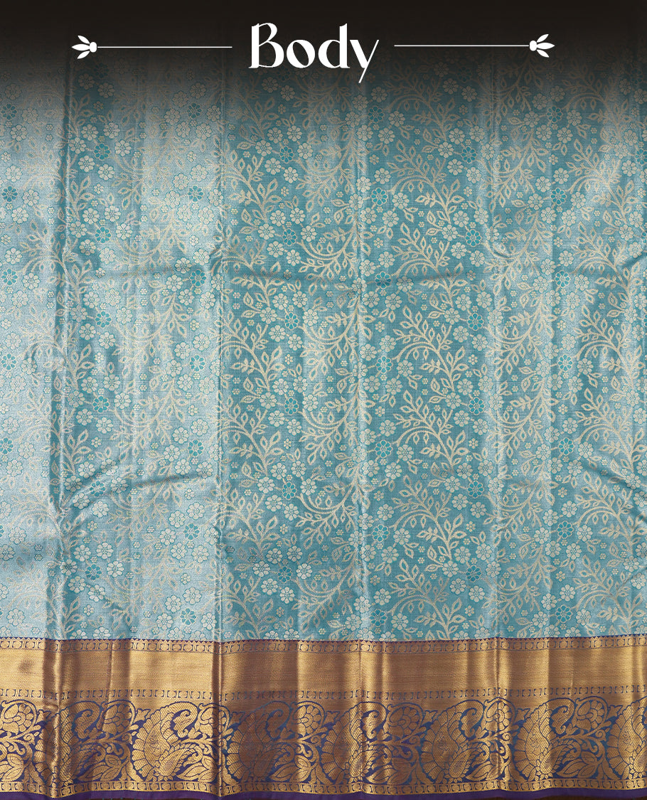 Blue colour tissue brocade saree with delicate floral and leaf motifs in antique gold zari work throughout body. Ornate gold border and pallu with traditional floral scrolls, navy blue accents. Includes coordinating blouse.