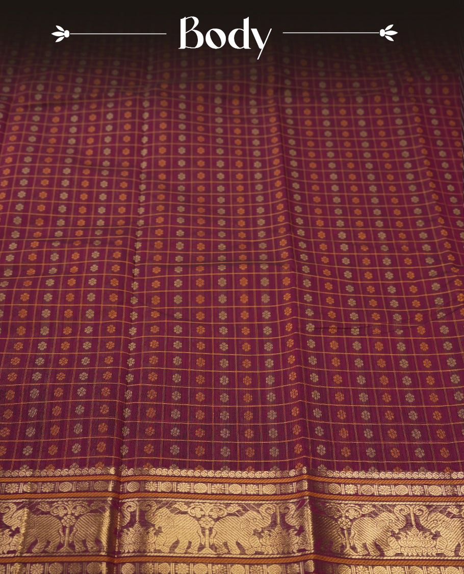Maroon colour pure Kanchi cotton saree featuring golden checks with floral motifs, enhanced by a grand zari border woven with majestic elephant patterns, exuding elegance and tradition & Comes with matching blouse.