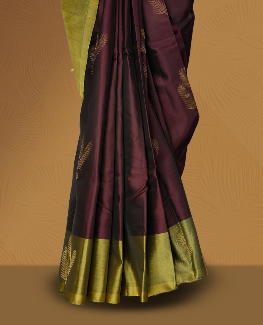 Maroon colour soft silk saree adorned with small golden buttas, enhanced by a shimmering light olive green zari border and pallu with delicate motifs & paired with a matching blouse.