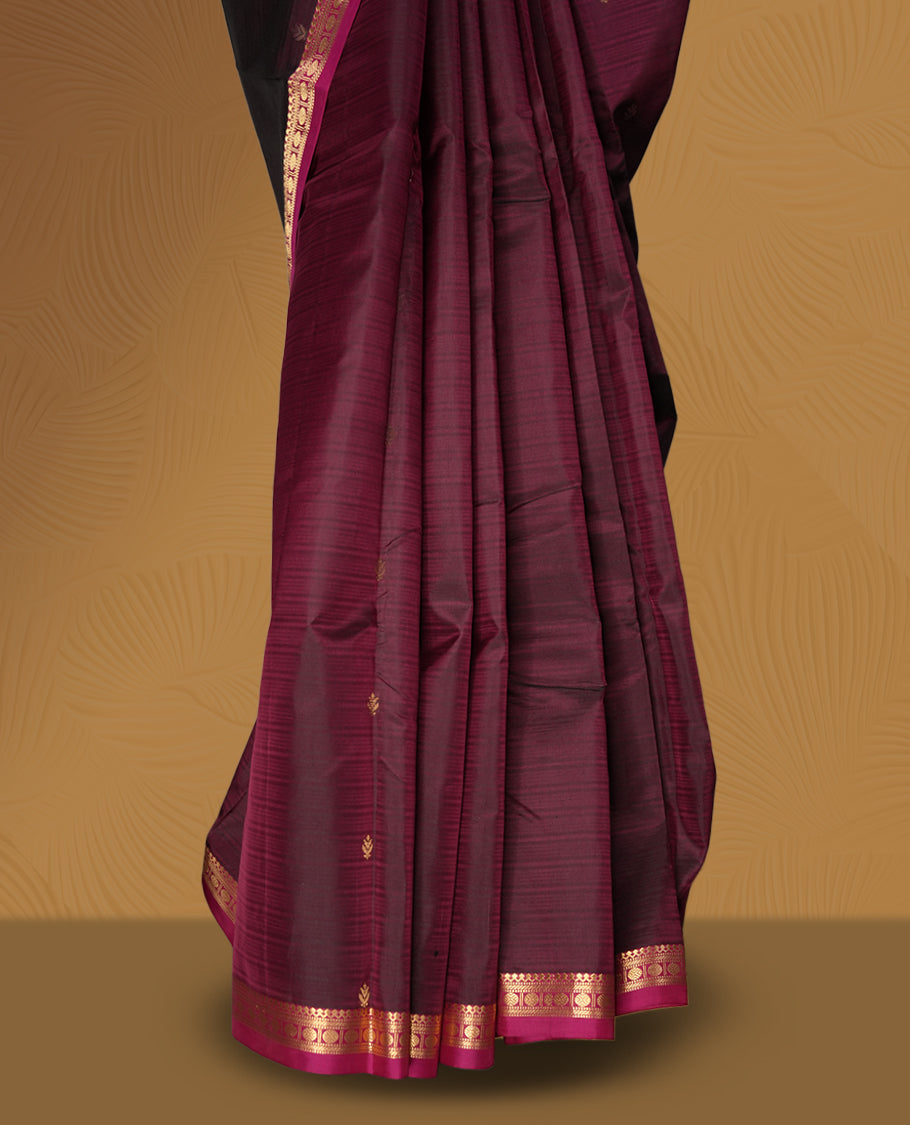 Dark maroon colour soft silk saree with subtle golden buttas, accentuated by a pink zari border and pallu & Paired with a matching blouse.