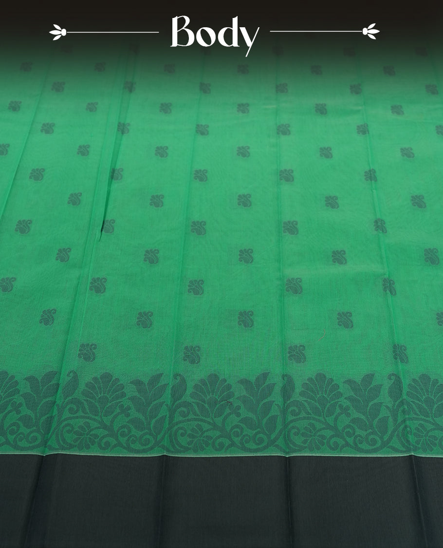 Emerald green colour silk cotton saree featuring subtle woven motifs throughout the body, enhanced by a striking grey contrast border and an intricately designed pallu with floral patterns & Comes with a matching blouse piece.