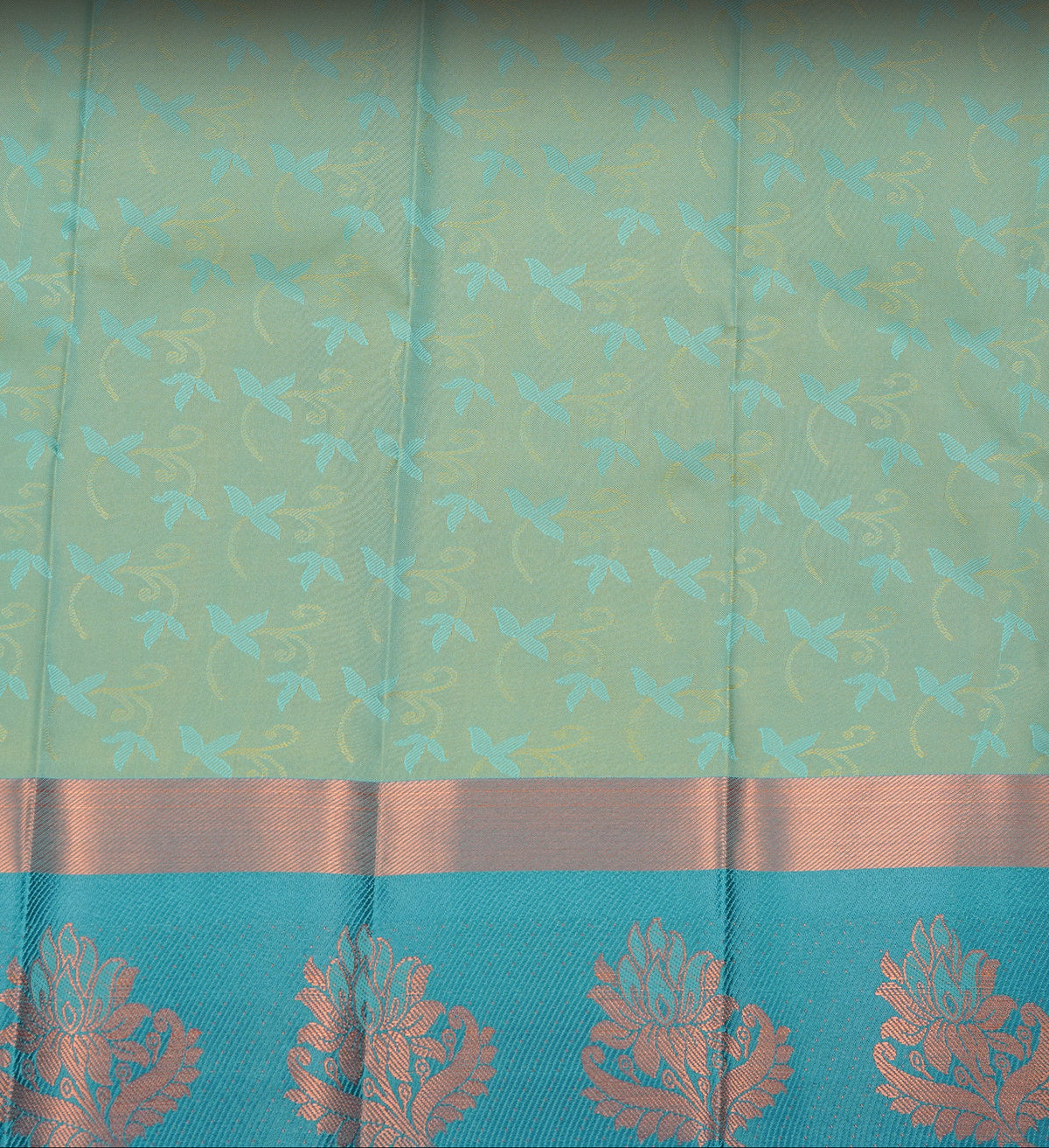 Sandalwood colour Semi silk saree featuirng Cream colour patterns on body, complemented by contrast Green colour with gold zari border, paired with matching blouse piece.