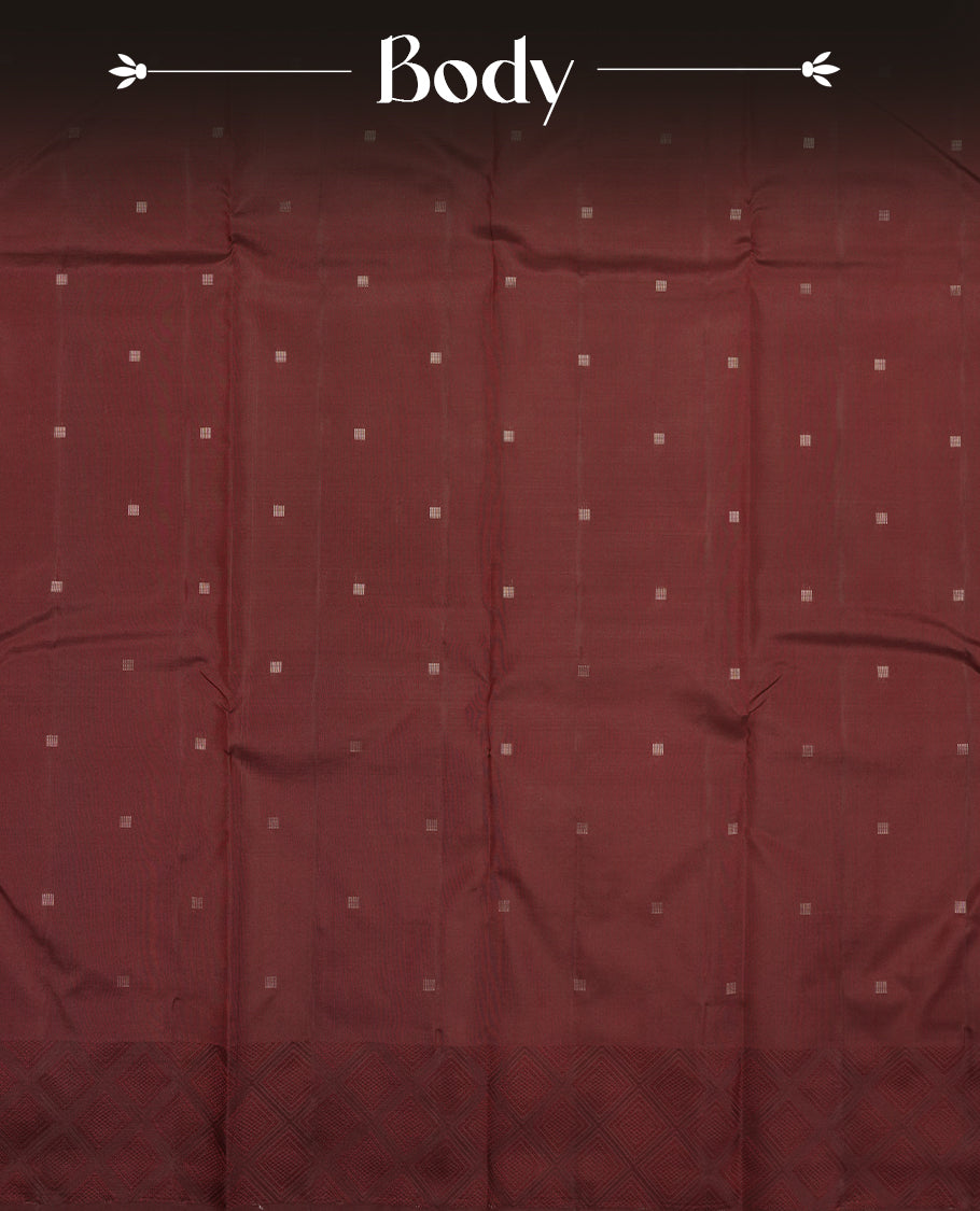 Dark maroon colour Vasundhara silk saree adorned with all-over tiny gold square motifs on the body, complemented by a self colour zari border and paired with a matching blouse piece.