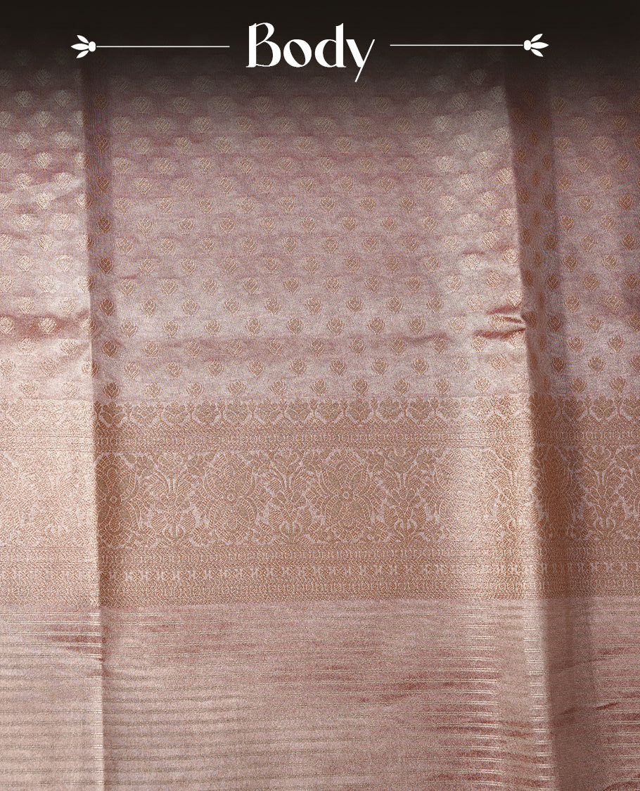 Pastel peach colour semi tissue silk saree featuring floral zari motifs on body, complemented by gold zari traditional border, paired with matching blouse piece.