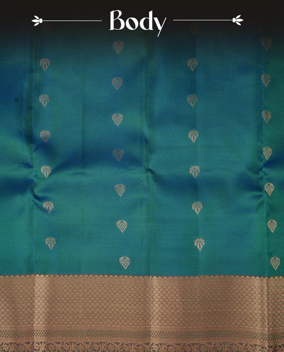 Peacock colour soft silk saree featuring gold zari motifs on the body, complemented by a contrast Magenta traditional zari floral kodi border and pallu, paired with a matching blouse piece.