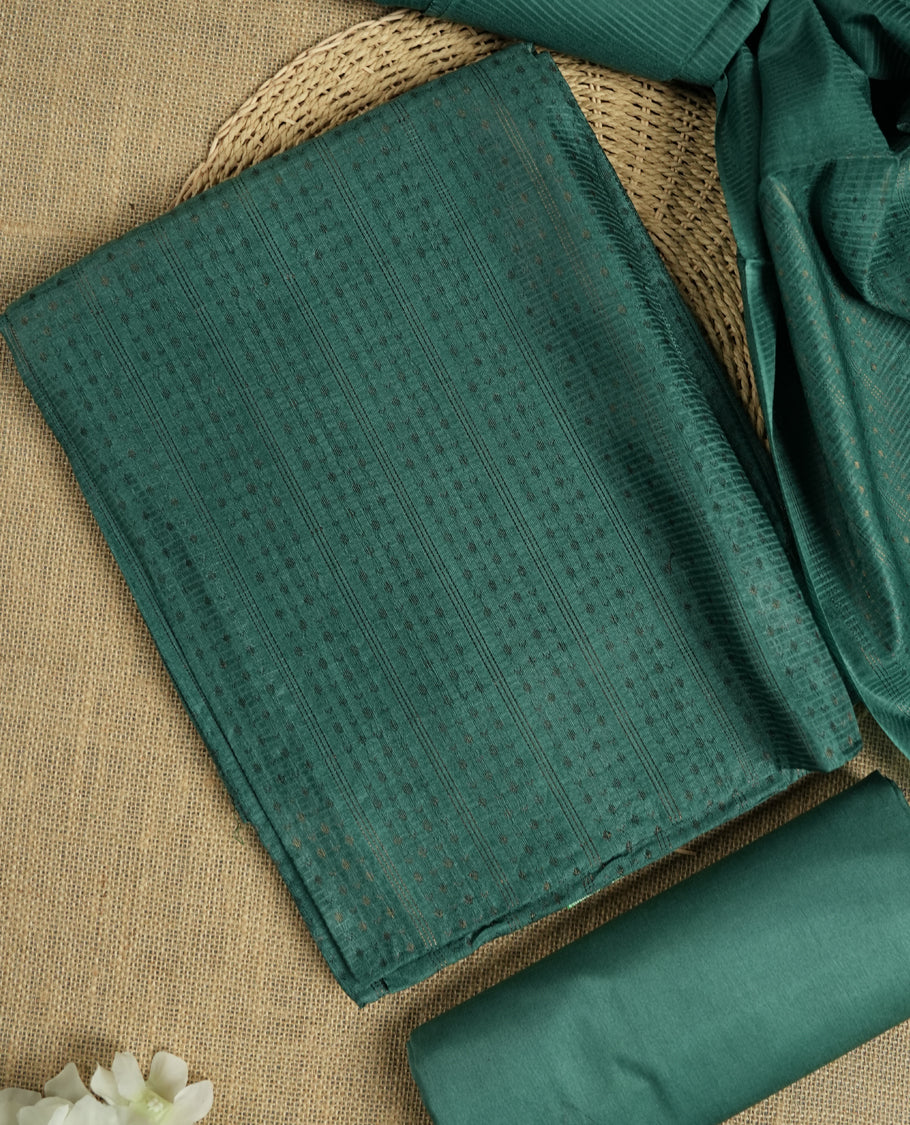Dark aqua green colour tussar suit material featuring a subtle self copper zari woven small motifs and vertical and stripped pattern on the body, paired with a lightweight matching dupatta with tassel edges and a plain bottom piece.