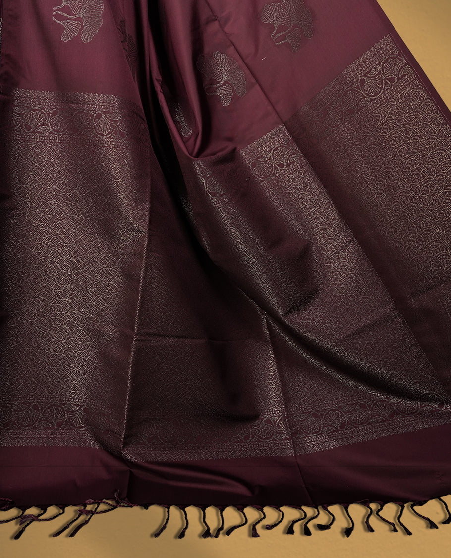 Deep brown colour semi soft silk saree, adorned with subtle floral woven motifs on the body & The design is elevated with an elegant zari border and pallu, paired with a matching blouse.