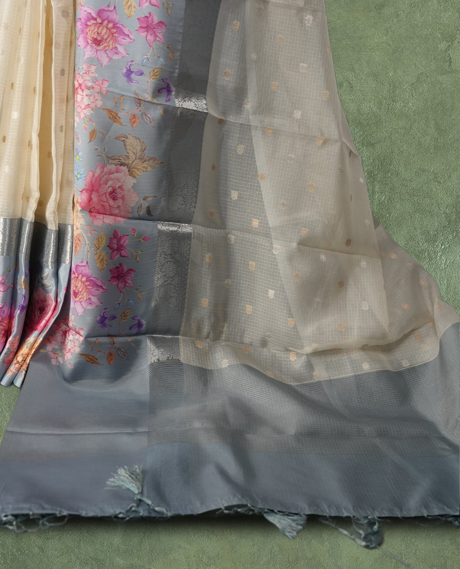 Ivory colour Kotta Tussar Silk saree features a vibrant digital floral print with small gold zari motifs on the body, and elegant grey colour banarasi border & Paired with a matching blouse,blending modern design with traditional elegance.
