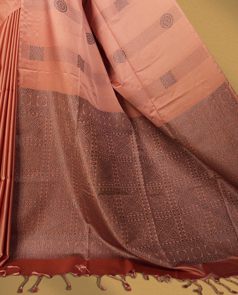 Amber rose colour semi soft silk saree, adorned with subtle self woven motifs on the body & The design is elevated with an elegant zari border & pallu with intricate detailing and tassel accents, paired with a matching blouse.