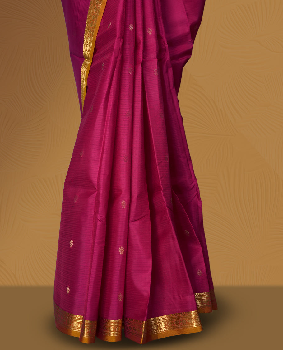 Magenta colour soft silk saree with golden buttas, enhanced by a vibrant orange zari border and pallu, paired with a matching blouse.