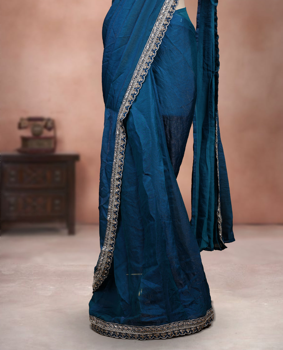Elegant Teal Blue Colour ready to wear saree adorned with rich silver zari and bead embroidery along the border and pallu, paired with a heavily embellished matching blouse for a grand festive look.