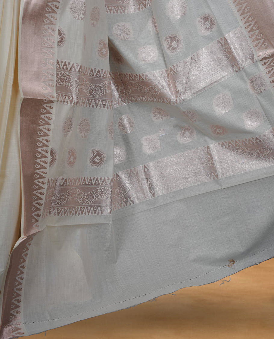 Off white colour cotton Kerala saree featuring subtle woven motifs, complemented by a soft rose gold zari border and rich traditional pallu, paired with a matching blouse.