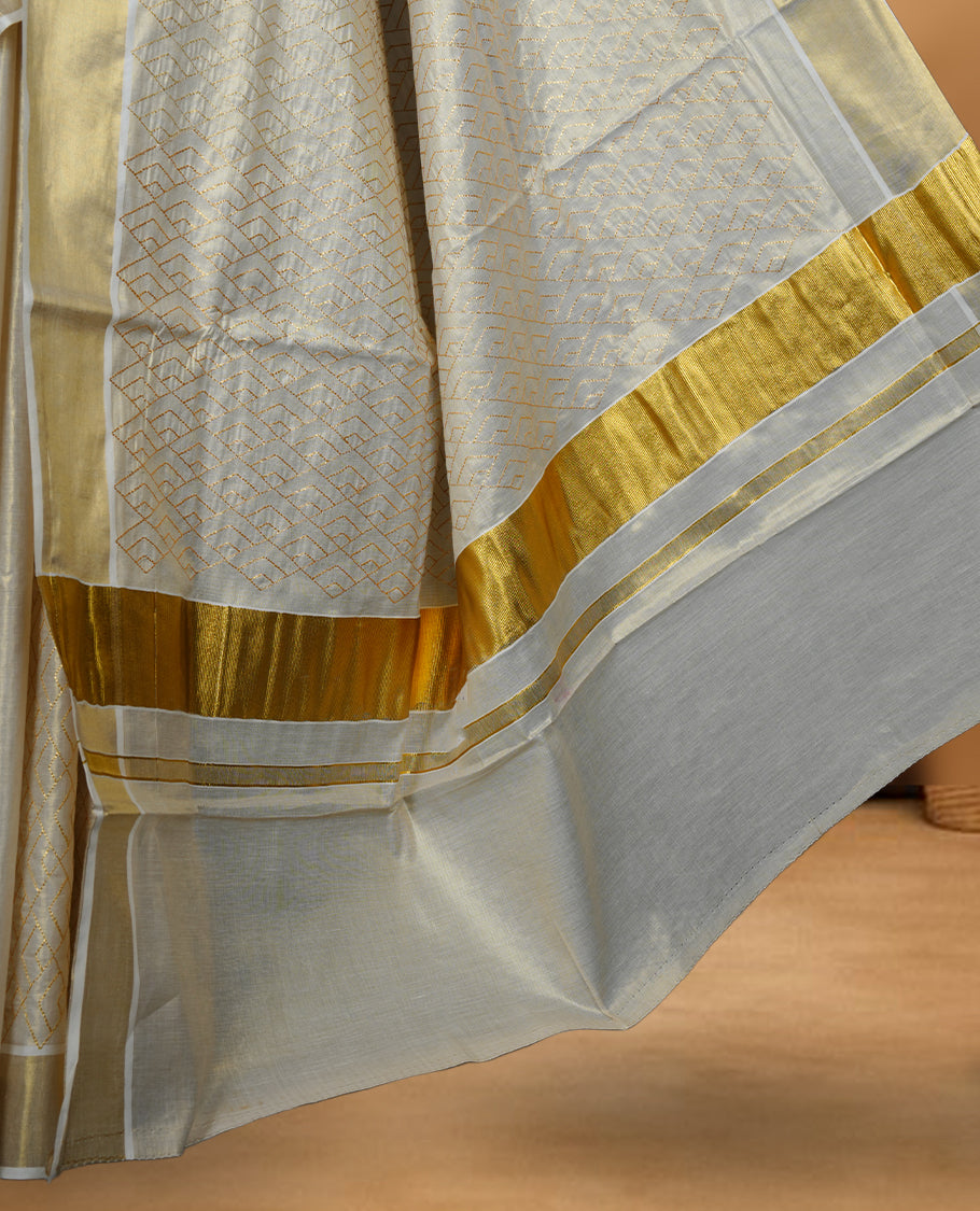Off white colour Tissue Kerala saree featuring an elegant all-over zari patterned body, complemented by a rich golden zari border and traditional pallu, paired with a matching blouse.