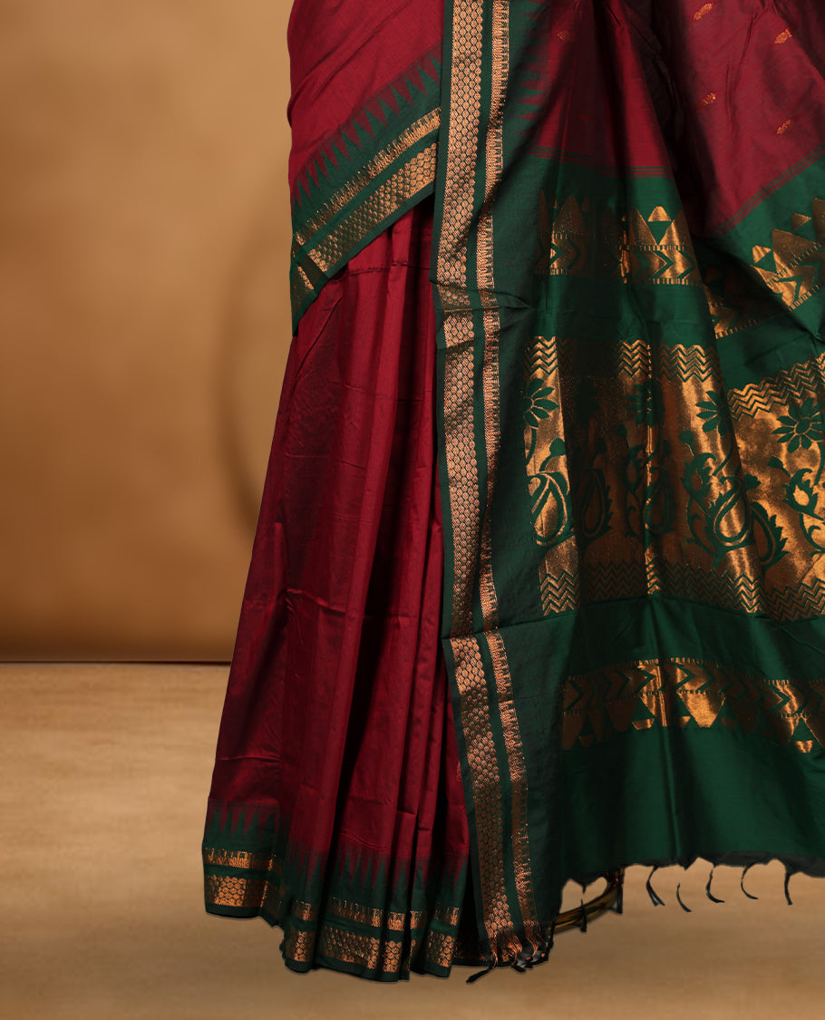 Maroon colour kalyani cotton saree featuring Antique zari motifs on body, contrast green colour border with geometric antique zari pattern, paired with matching blouse piece.