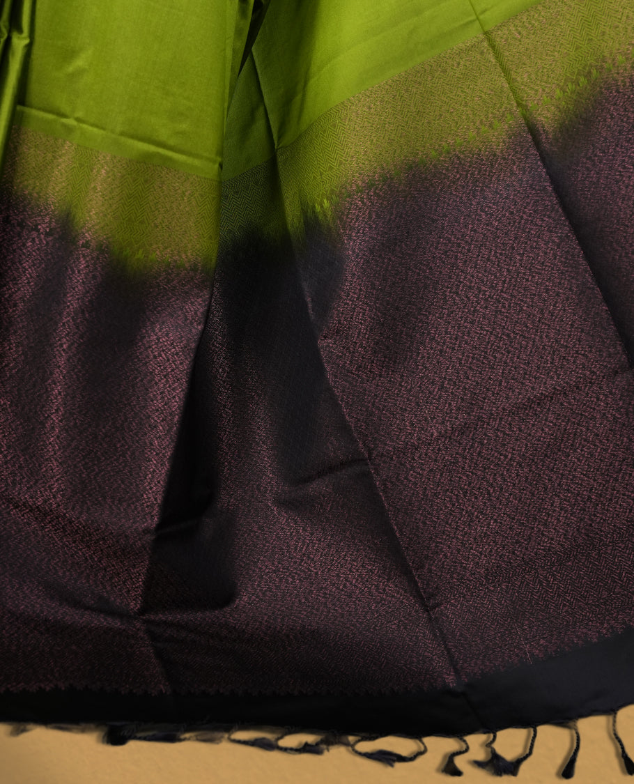 Olive green colour semi soft silk saree adorned with delicate woven self motifs on the body, complemented by a rich contrast navy blue colour woven pallu with intricate detailing and tassel accents & Comes with a matching blouse piece.