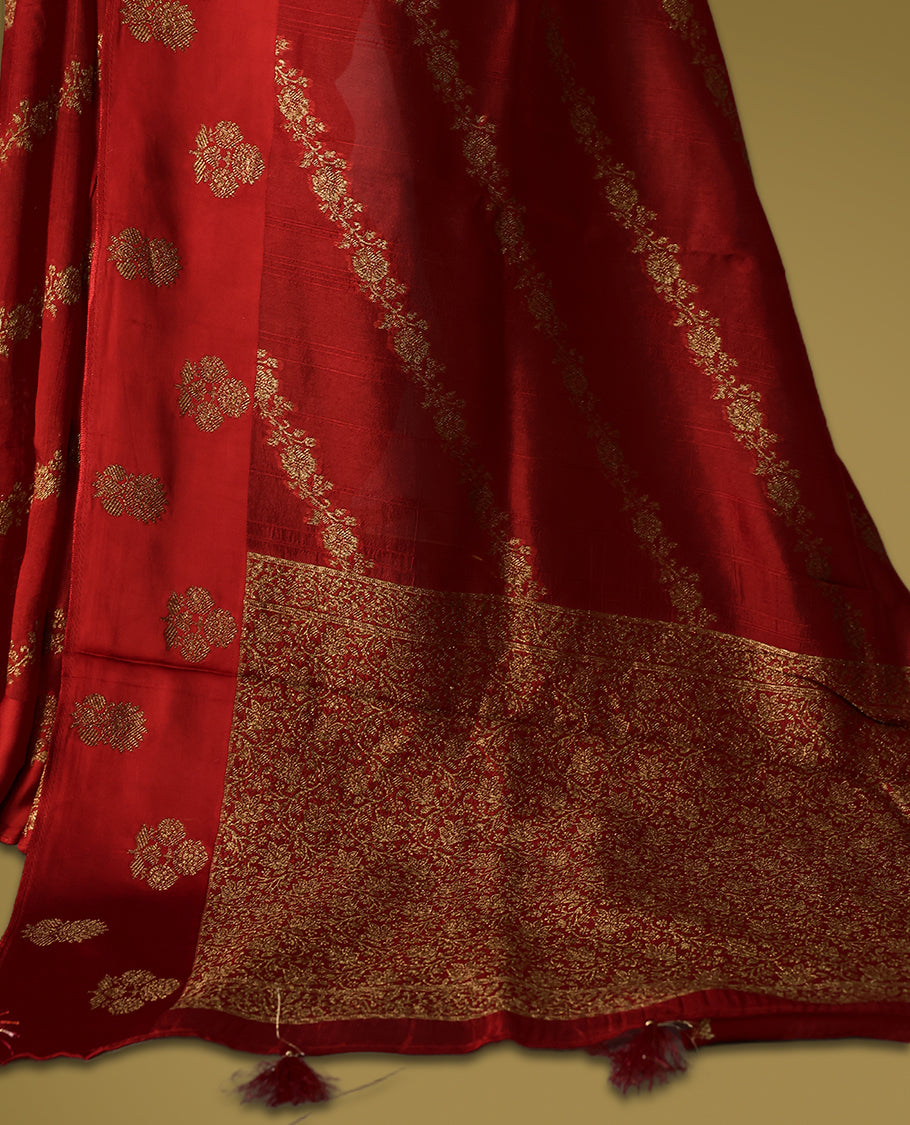 Cherry red semi Banaras tussar saree adorned with golden floral motifs in diagonal patterns across the body and a finely woven zari border, finished with a rich golden pallu, paired with a matching blouse.