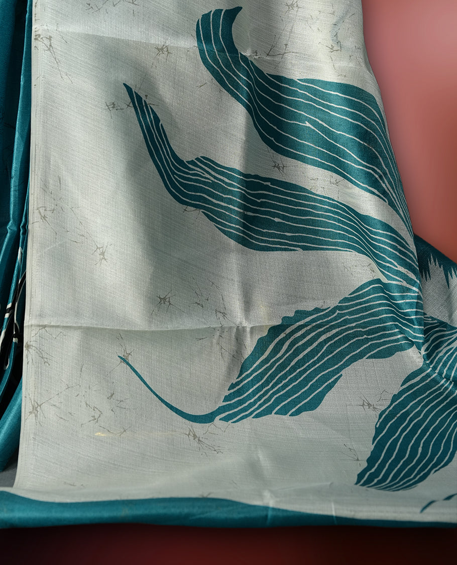 Teal blue colour saree adorned with bold off white floral prints, blending tradition with a modern twist & paired with a matching blouse.