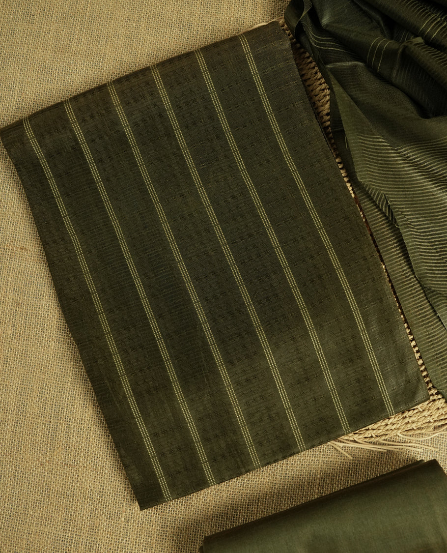 Army green colour tussar suit material featuring a subtle self woven pattern and vertical lines on the body, paired with a lightweight matching dupatta with tassel edges and a plain bottom piece.