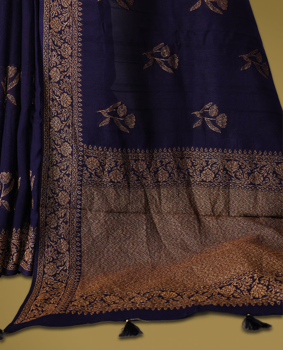 Navy blue semi Banaras tussar saree adorned with golden floral motifs in diagonal patterns across the body and a finely woven zari border, finished with a rich golden pallu, paired with a matching blouse.