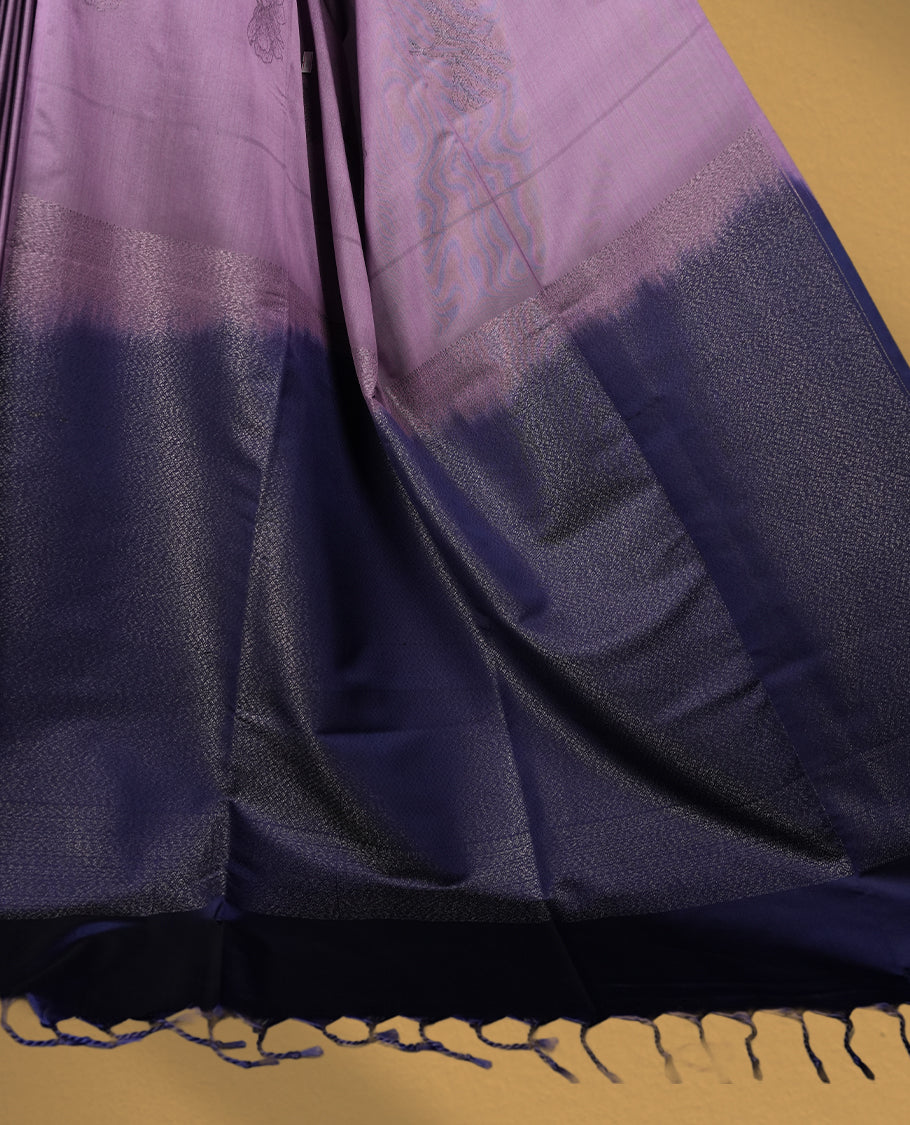 Royal purple colour semi soft silk saree adorned with delicate woven floral motifs on the body, complemented by a rich contrast deep blue colour woven pallu with intricate detailing and tassel accents & Comes with a matching blouse piece.