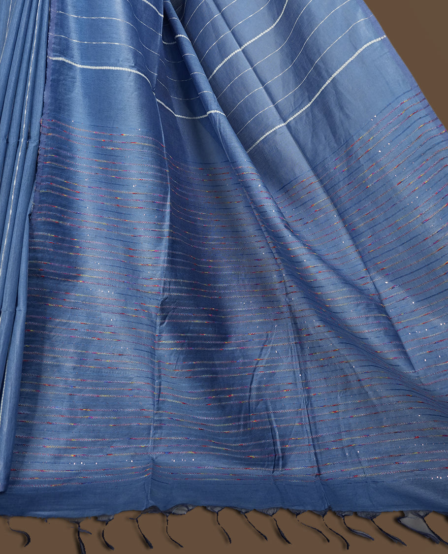 Blue colour semi jute saree with vertical white stripes for a modern appeal, Soft texture, sleek border, tassel pallu, and subtle multicolor detailing & Includes matching blouse piece for a complete look.