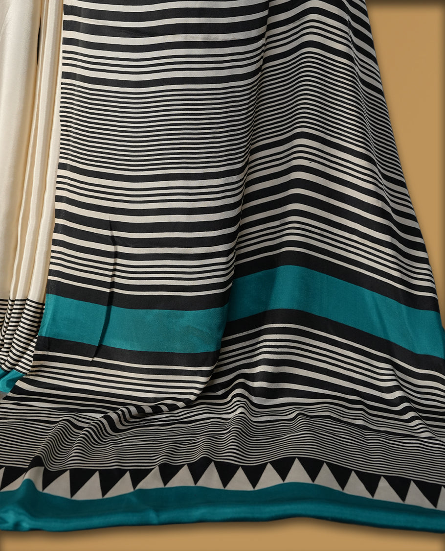 Ivory white colour saree with bold black polka dots and fine stripe detailing, elevated by a vibrant teal border & The striking pallu design adds charm. Lightweight and elegant, paired with matching blouse.