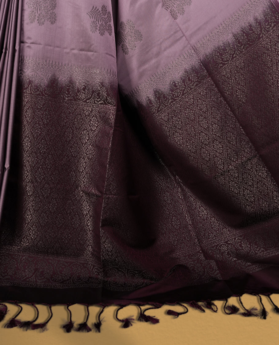 Greyish lavender colour semi soft silk saree, beautifully designed with rich floral woven motifs & The look is enhanced by a rich contrast deep wine border and pallu with tassels, paired with a matching blouse.