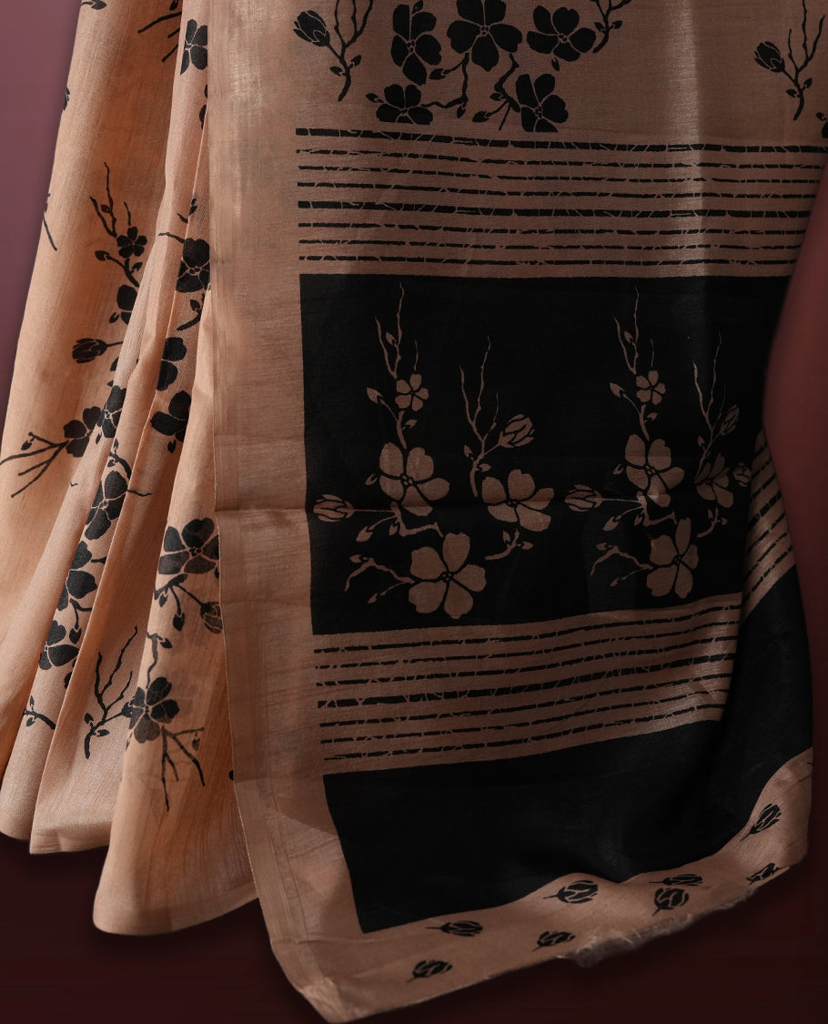 Pastel peach colour saree with delicate black floral prints spread across the body, The black pallu features coordinated floral motifs and stripes, Finished with a sleek border and paired with a matching blouse.