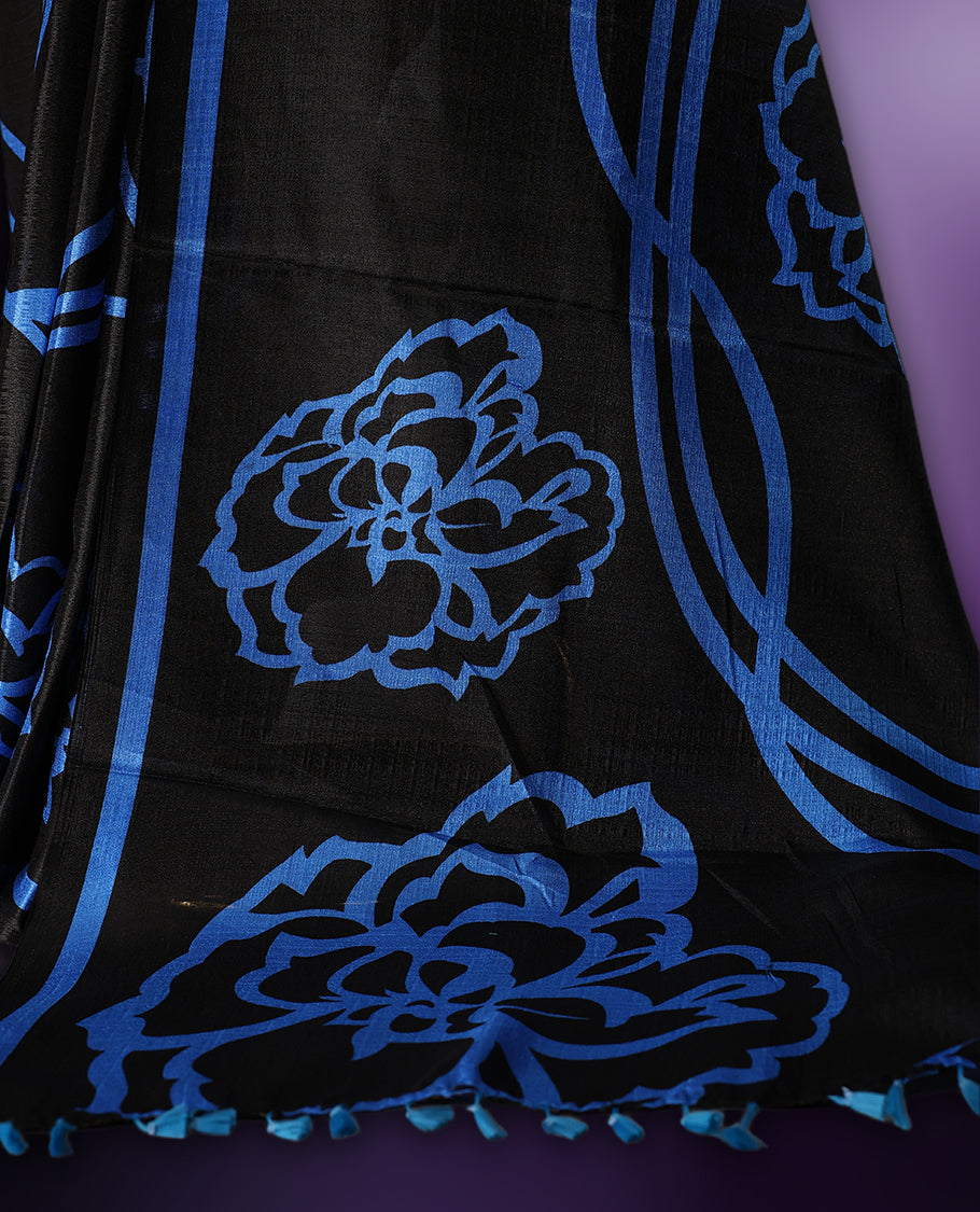 Elegant black colour art silk saree with bold blue floral prints and matching border & Accentuated with a tassel detailed pallu, its perfect for festive evenings or parties. Comes with an unstitched blouse piece.