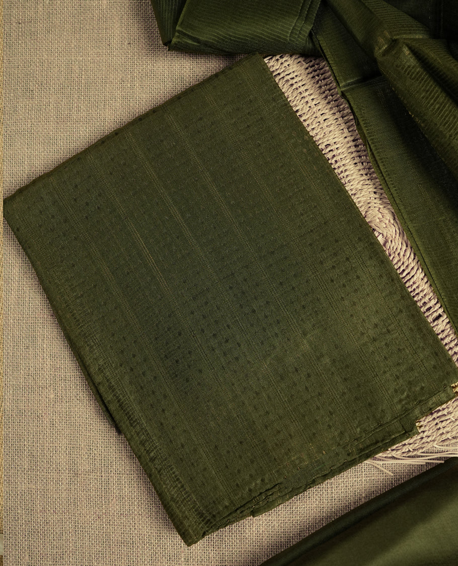 Dark Army green colour tussar suit material featuring a subtle self copper zari woven motifs and vertical and stripped pattern on the body, paired with a lightweight matching dupatta with tassel edges and a plain bottom piece.