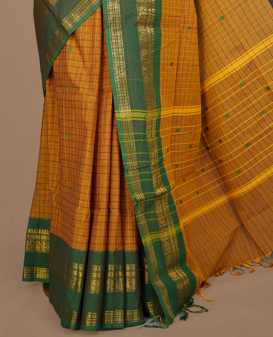 Mustard colour chettinad cotton featuring check pattern on body, complemented by contrast chocolate brown colour with gold zari border, paired with matching blouse piece.