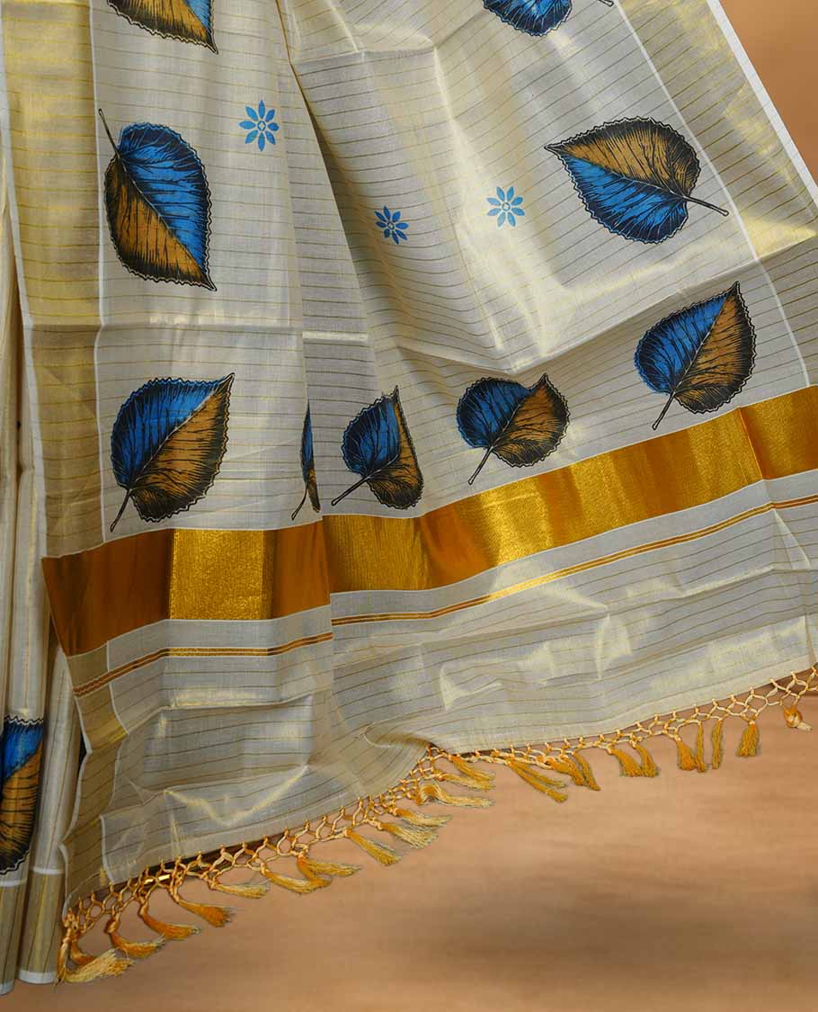 Off white colour Tissue Kerala saree featuring a subtle striped body with elegant blue and mustard leaf prints, complemented by a classic golden zari border and tasselled pallu, paired with a matching blouse.