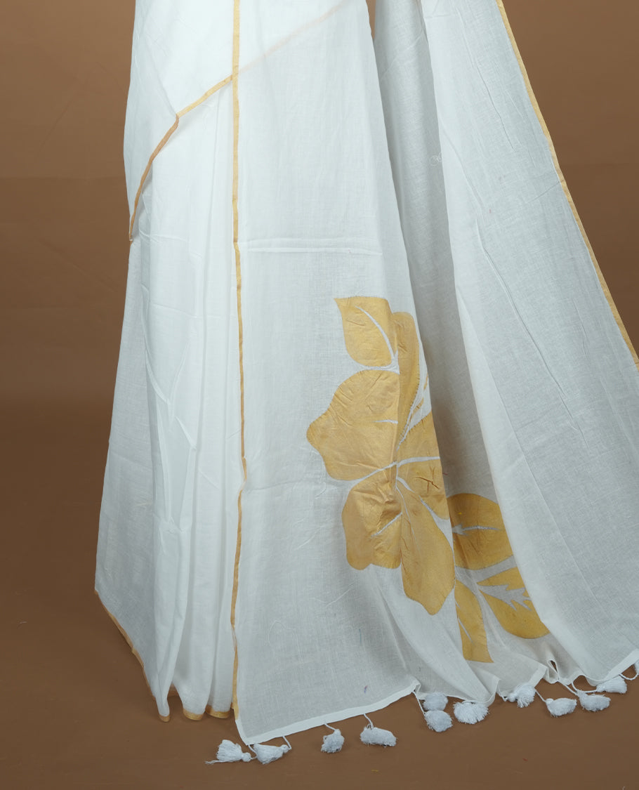 White coloured mul cotton saree featuring bold gold-tone floral motifs across the body, designed without a border and comes without a blouse piece.