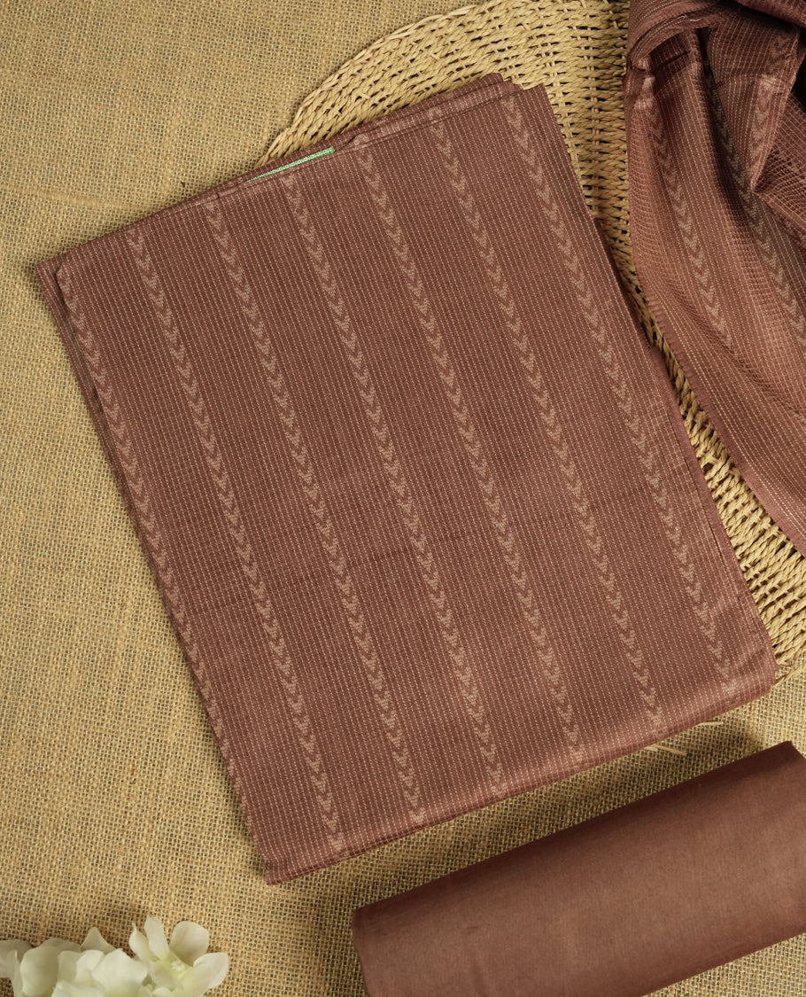 Dusty brown colour tussar suit material adorned with intricate woven patterns and subtle motifs, exuding ethnic elegance & Paired with a beautifully bordered dupatta and a matching plain bottom.