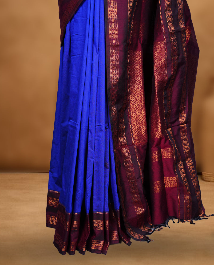 Royal blue colour saree with subtle zari motifs, complemented by a rich maroon zari border and traditional pallu, paired with a matching blouse.