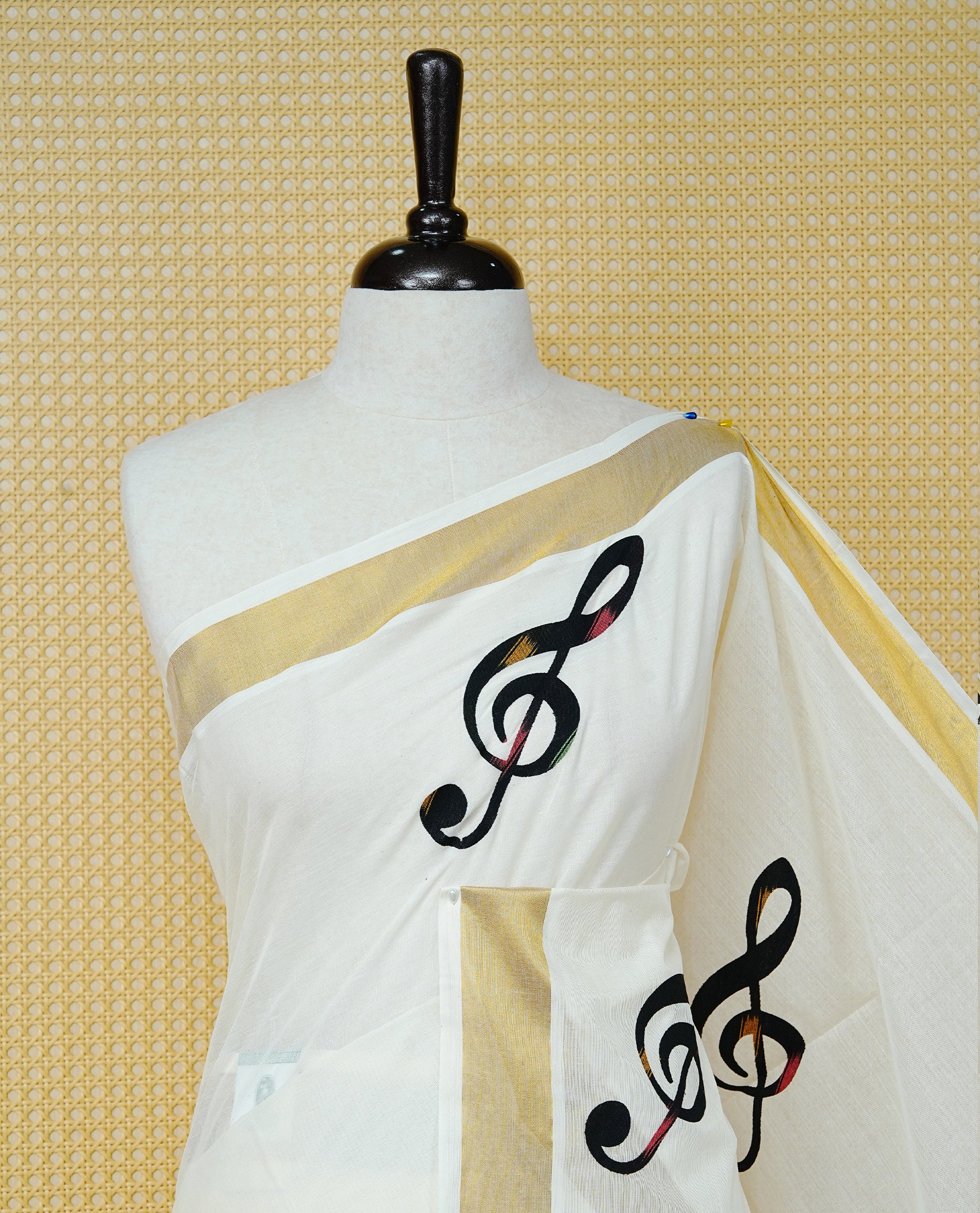 Cream Colour Kerala Saree Featuring Black Instrument Motifs And A Classic Gold Zari Border, Paired With A Matching Blouse Piece.