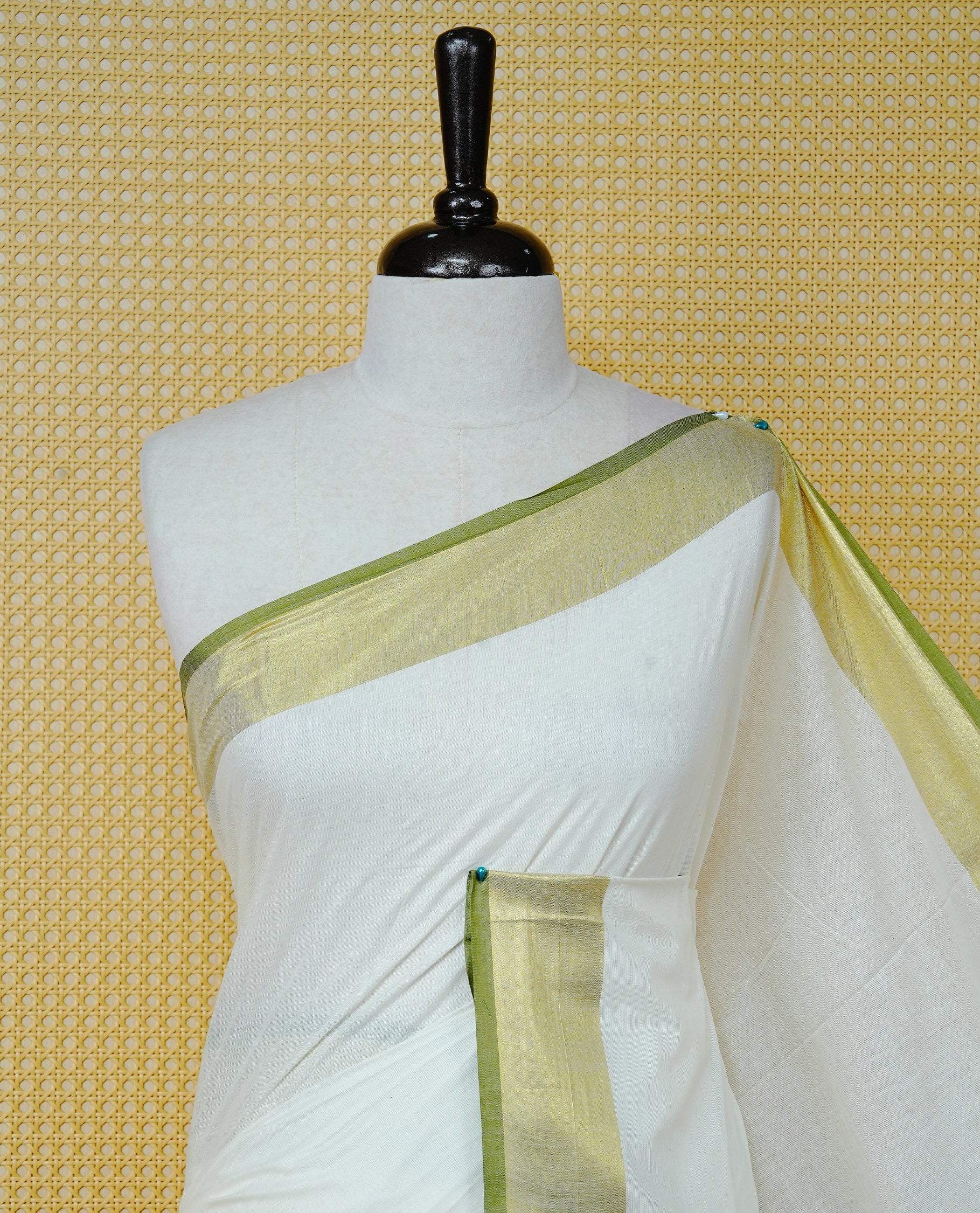Cream Colour Cotton Kerala Saree Featuring A Plain Body, Enhanced With A Gold Zari & Light Green Colour Border, A Traditional Gold Zari Pallu, Light Green Tassels, And A Matching Blouse Piece.