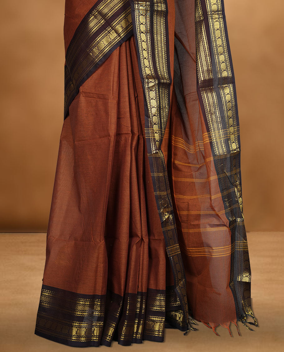 Brown colour chettinad cotton saree featuring plain body, contrast Deep purple colour with traditional gold zari border paired with matching blouse.