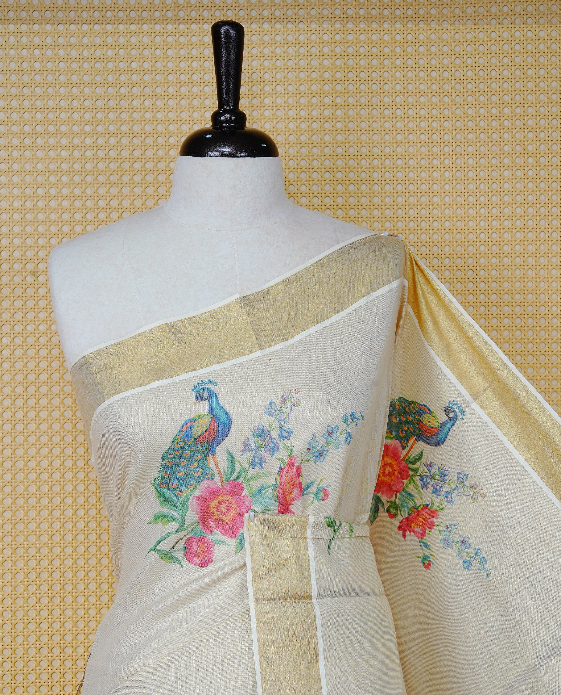 Cream Colour Tissue Kerala Saree Featuring A Digital Peacock & Floral Printed Body & Pallu , Beautifully Enhanced With A Classic Gold Zari Border And Blue & Baby Pink Tassels, Paired With A Matching Blouse Piece